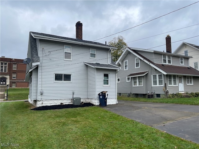 back of house featuring central air condition unit and a lawn