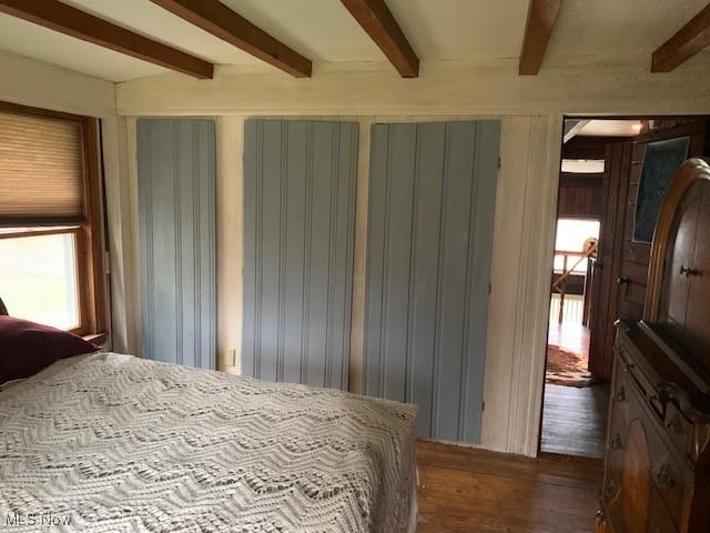 bedroom featuring dark wood-type flooring and beamed ceiling