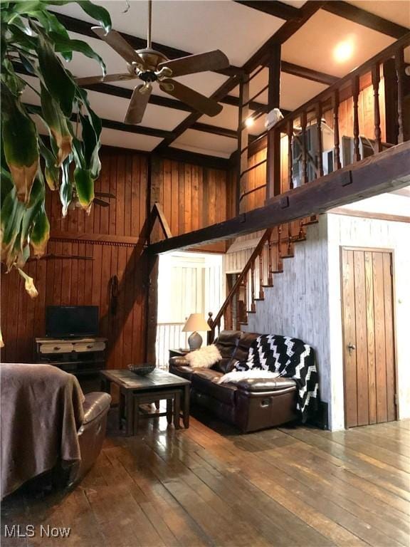 interior space featuring wood-type flooring, wooden walls, and ceiling fan