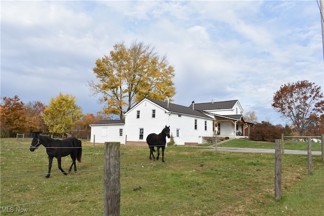 view of side of property with a rural view and a lawn