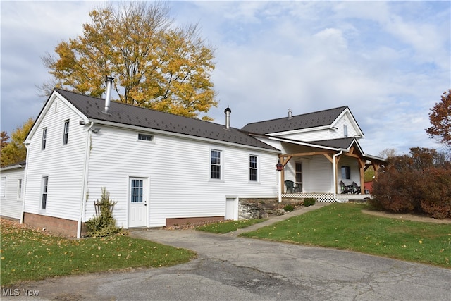 view of side of property with a lawn and covered porch