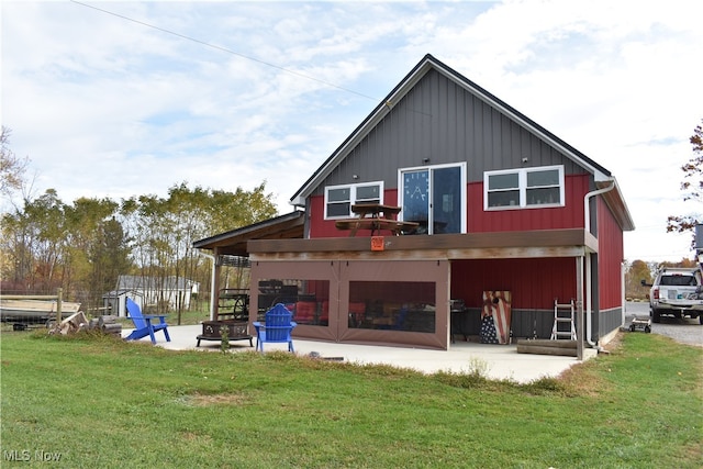 back of property with a yard, a fire pit, and a patio area