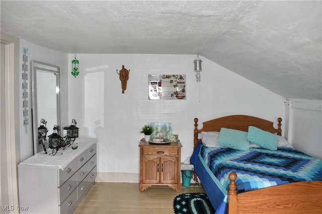 bedroom with light hardwood / wood-style floors and a textured ceiling