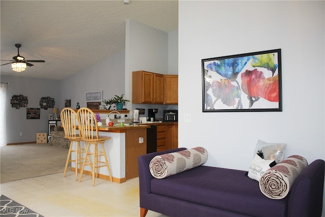 kitchen with kitchen peninsula, a kitchen breakfast bar, light colored carpet, vaulted ceiling, and ceiling fan