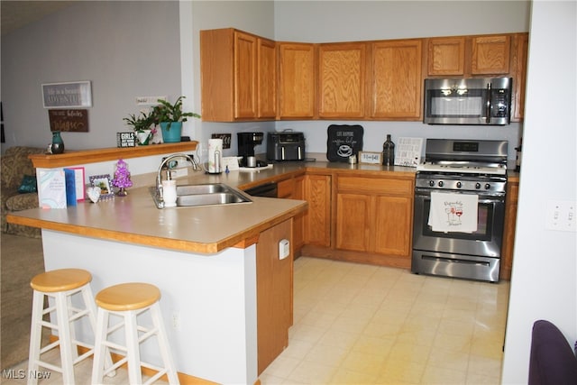 kitchen featuring kitchen peninsula, a kitchen bar, stainless steel appliances, and sink