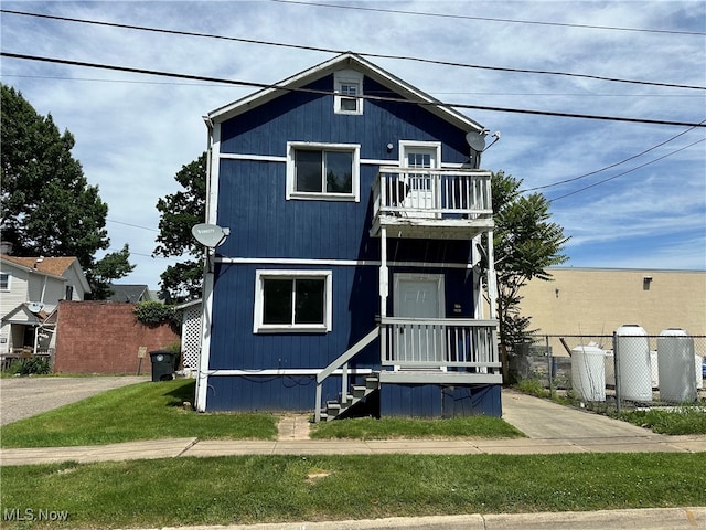 view of front of property with a balcony and a front lawn