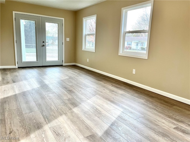 spare room featuring french doors, a healthy amount of sunlight, and light hardwood / wood-style floors