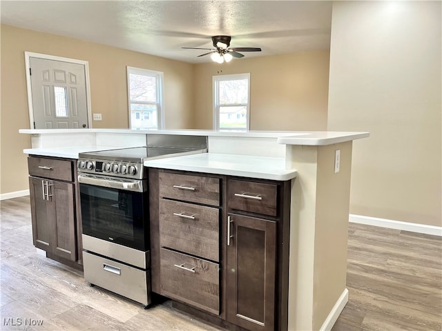 kitchen featuring ceiling fan, dark brown cabinetry, light wood-type flooring, and stainless steel stove