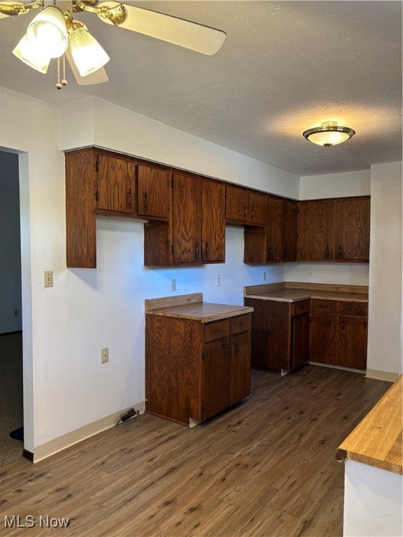 kitchen featuring dark brown cabinetry, a textured ceiling, ceiling fan, and dark wood-type flooring