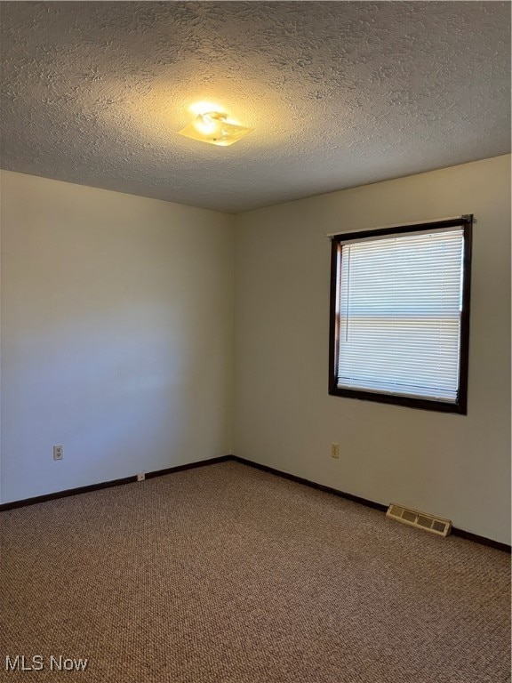 unfurnished room featuring carpet flooring and a textured ceiling