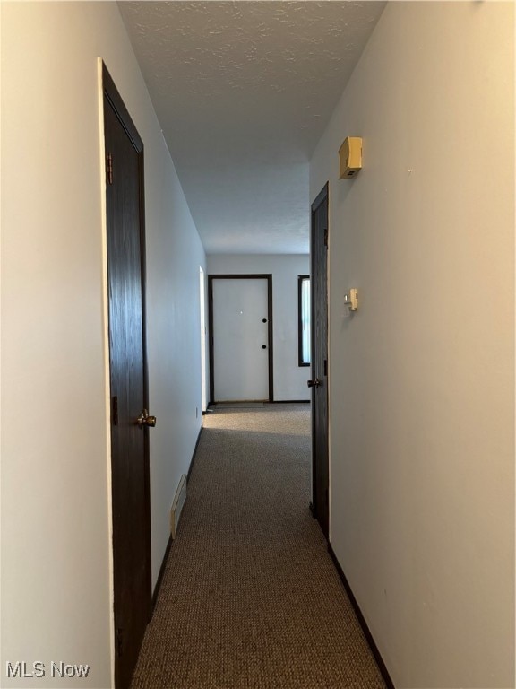 hall with dark colored carpet