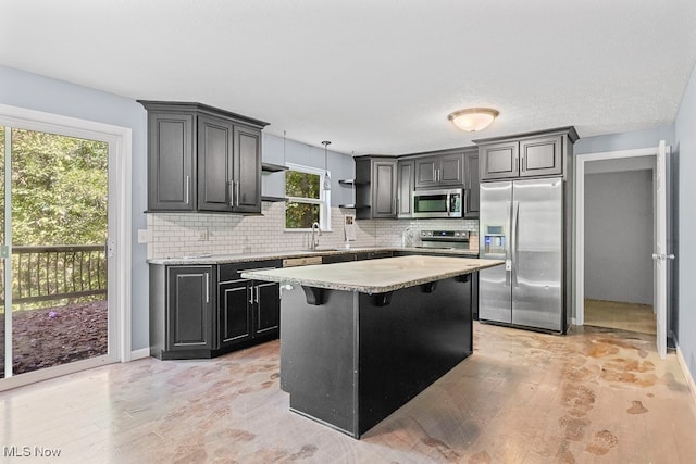 kitchen featuring stainless steel appliances, a kitchen island, plenty of natural light, and a breakfast bar area