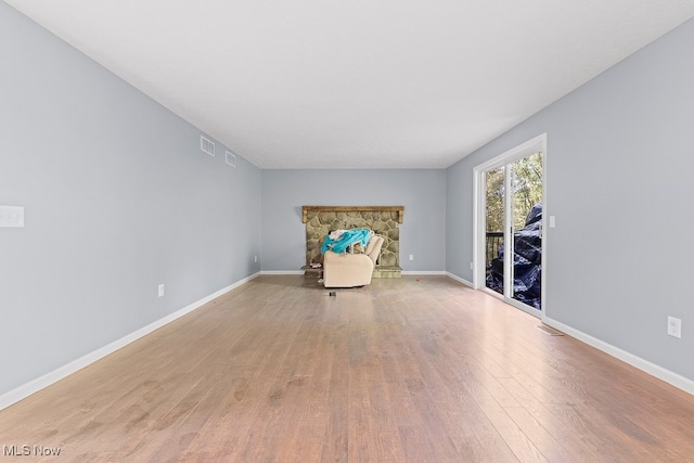 unfurnished room featuring a stone fireplace and light hardwood / wood-style flooring