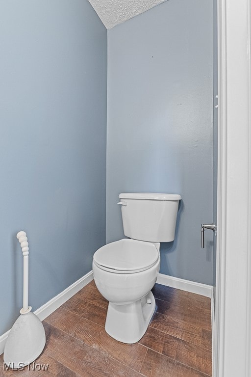 bathroom featuring wood-type flooring, a textured ceiling, and toilet