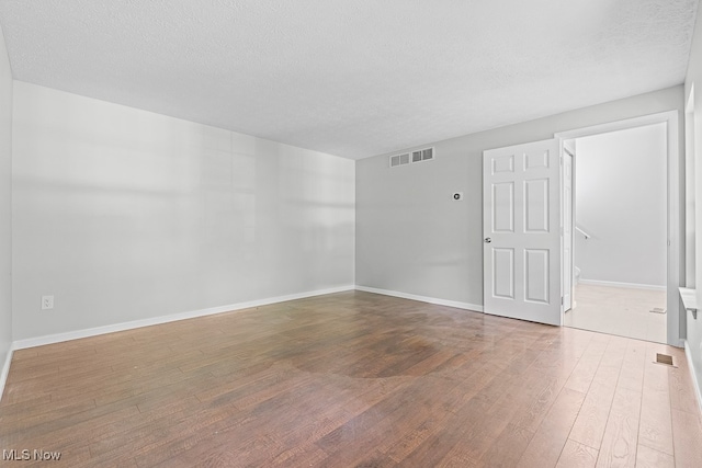 unfurnished room featuring wood-type flooring and a textured ceiling