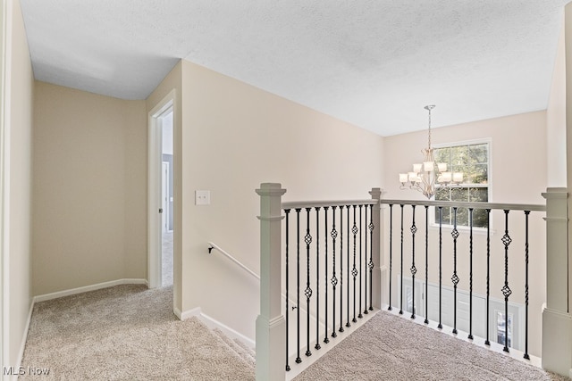 stairway featuring carpet, a textured ceiling, and an inviting chandelier