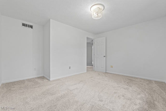 unfurnished room with a textured ceiling and light colored carpet