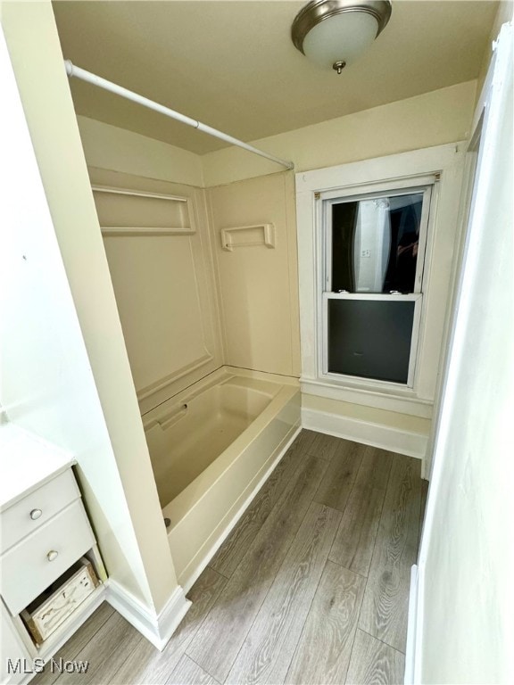 bathroom featuring washtub / shower combination, vanity, and hardwood / wood-style flooring