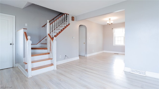 stairway featuring hardwood / wood-style floors and a notable chandelier