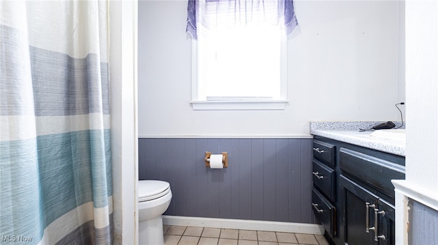 bathroom with tile patterned floors, wooden walls, vanity, and toilet