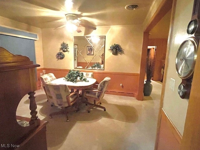 dining area with ceiling fan and light colored carpet