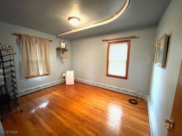 unfurnished bedroom with hardwood / wood-style floors and a baseboard radiator