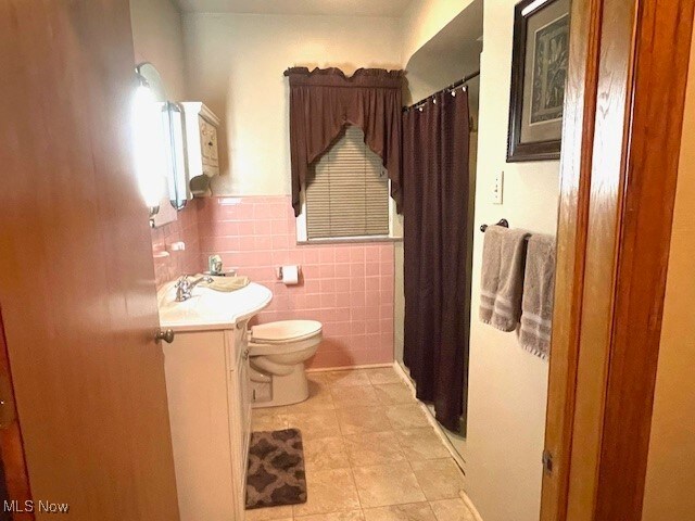 bathroom featuring tile patterned floors, vanity, tile walls, toilet, and curtained shower