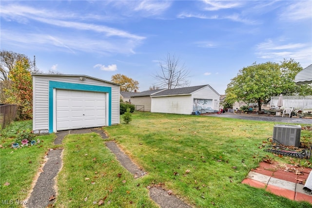 view of yard featuring an outbuilding, a garage, and central AC unit