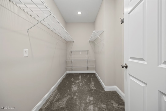 walk in closet with dark carpet