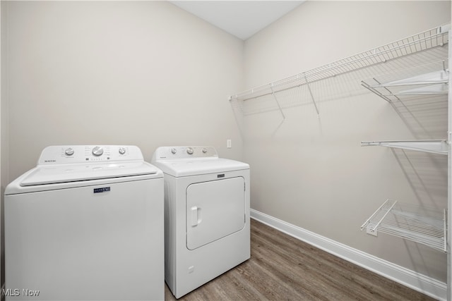 clothes washing area featuring washing machine and dryer and hardwood / wood-style flooring