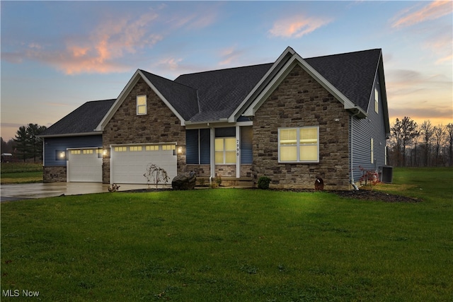 craftsman house with a lawn, central AC unit, and a garage