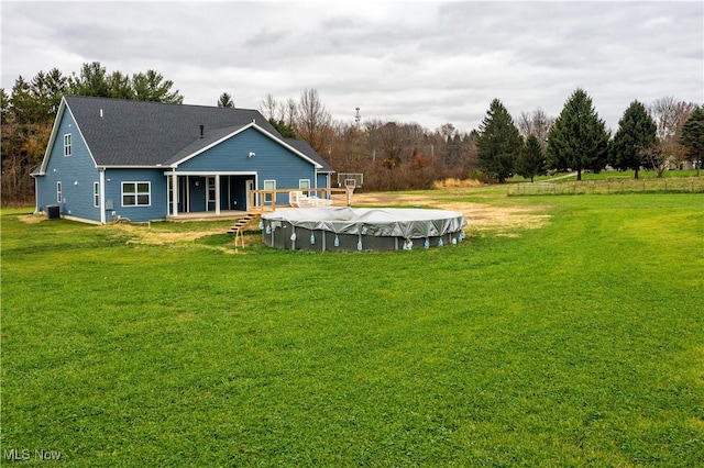 back of property with a lawn, a swimming pool side deck, and central AC unit