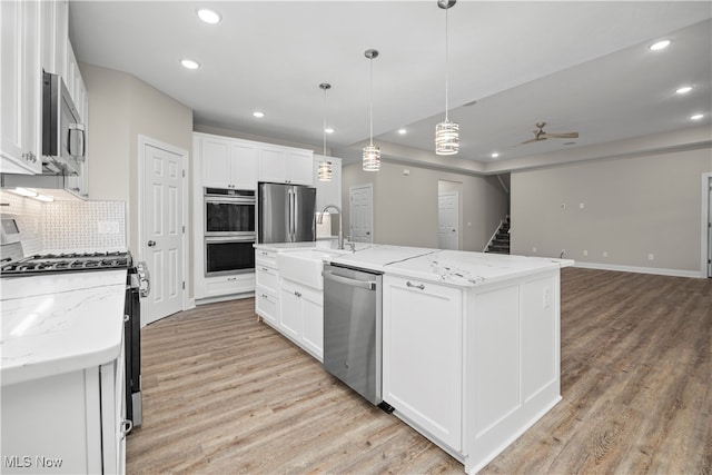 kitchen with white cabinets, appliances with stainless steel finishes, and a kitchen island with sink