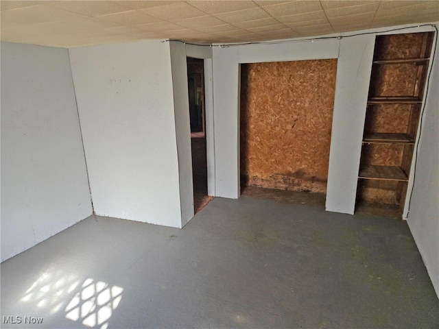 empty room with a drop ceiling and concrete flooring