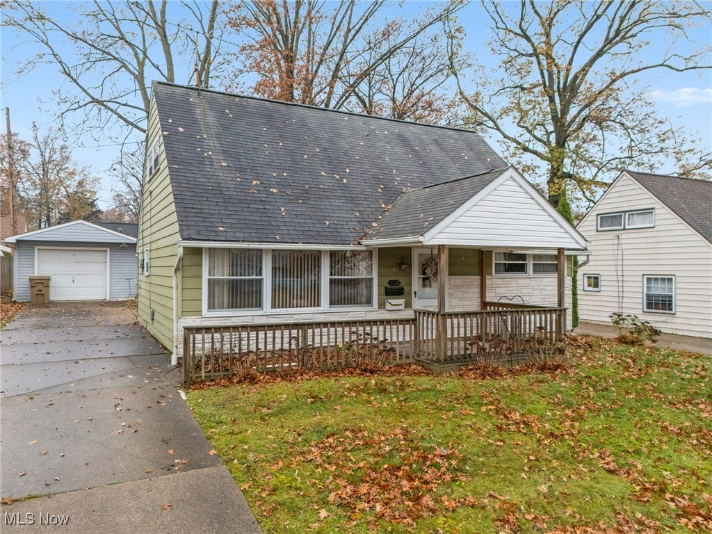 view of front facade with a front yard, a porch, a garage, and an outdoor structure