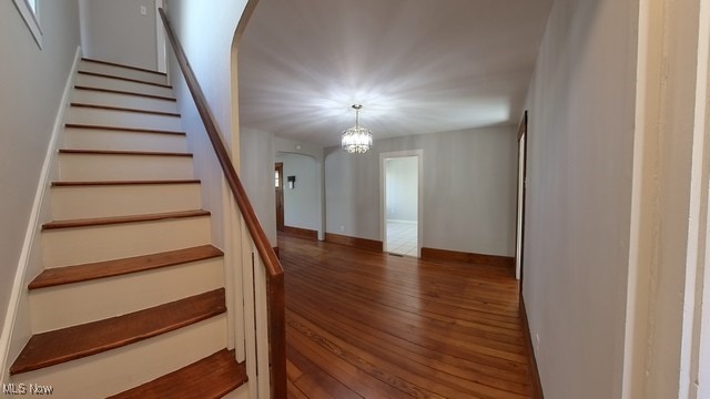 stairway featuring hardwood / wood-style floors and a notable chandelier