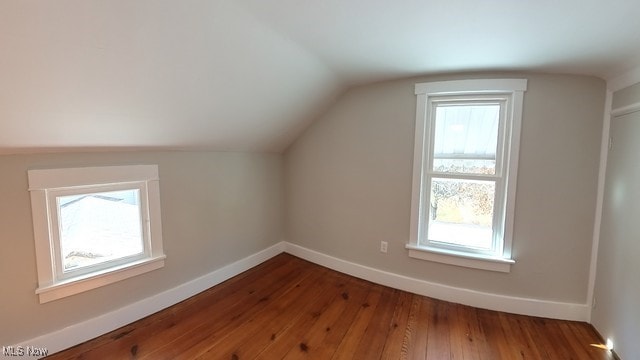 additional living space featuring hardwood / wood-style floors, plenty of natural light, and vaulted ceiling