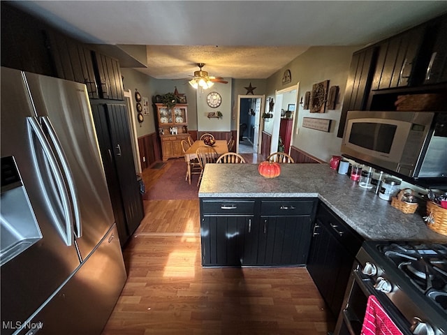 kitchen featuring dark stone counters, ceiling fan, stainless steel appliances, and dark hardwood / wood-style floors