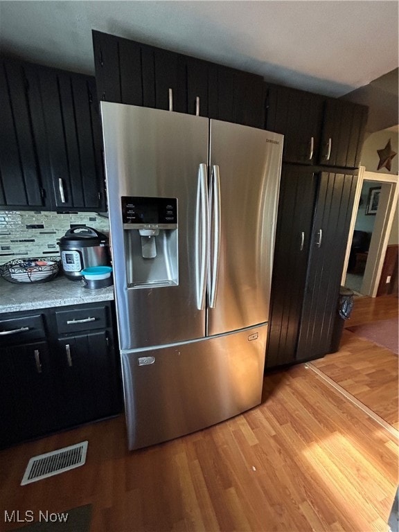 kitchen with decorative backsplash, stainless steel fridge with ice dispenser, and light hardwood / wood-style flooring