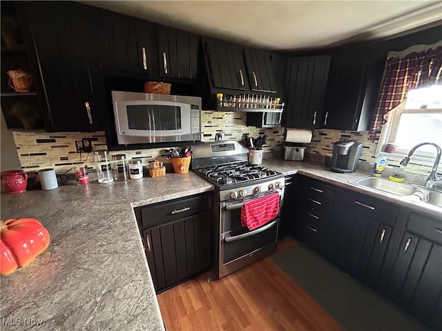 kitchen with decorative backsplash, light wood-type flooring, sink, and appliances with stainless steel finishes