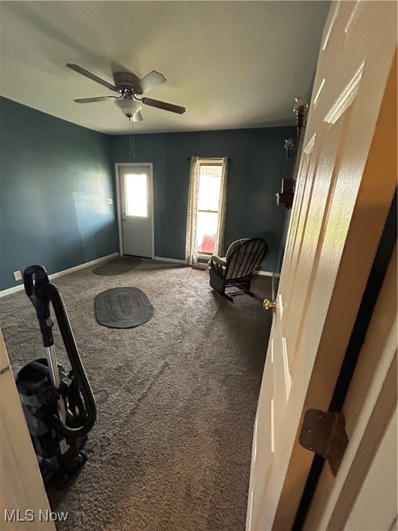 living area with ceiling fan and carpet