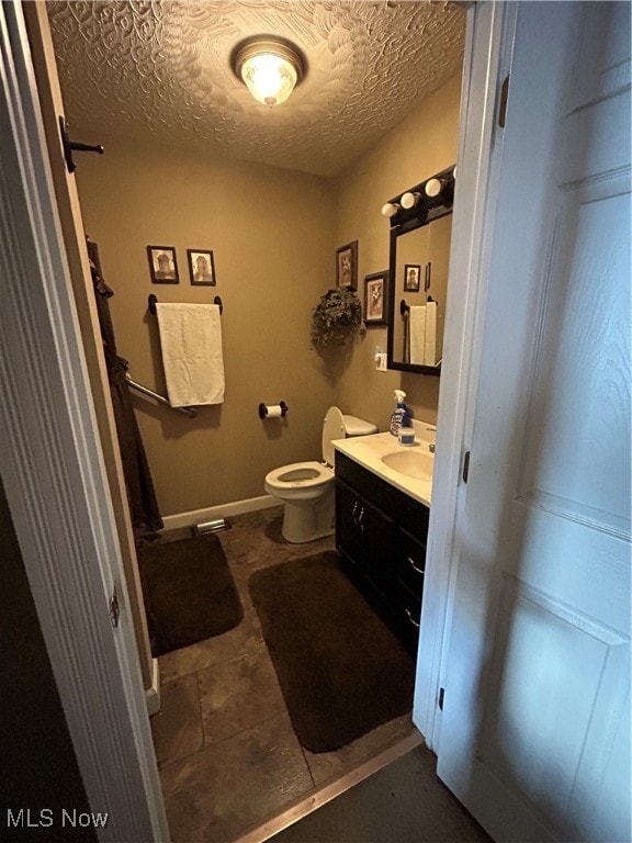 bathroom with vanity, toilet, and a textured ceiling