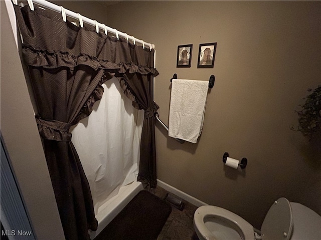 bathroom featuring curtained shower and toilet