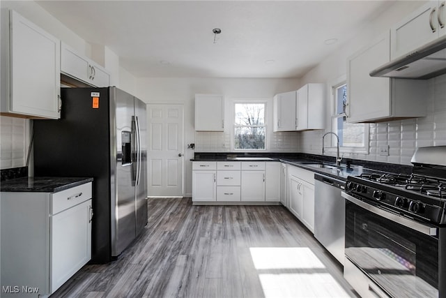 kitchen featuring hardwood / wood-style floors, backsplash, sink, white cabinetry, and stainless steel appliances