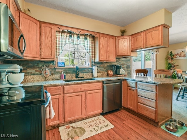 kitchen with tasteful backsplash, kitchen peninsula, light hardwood / wood-style flooring, and stainless steel appliances