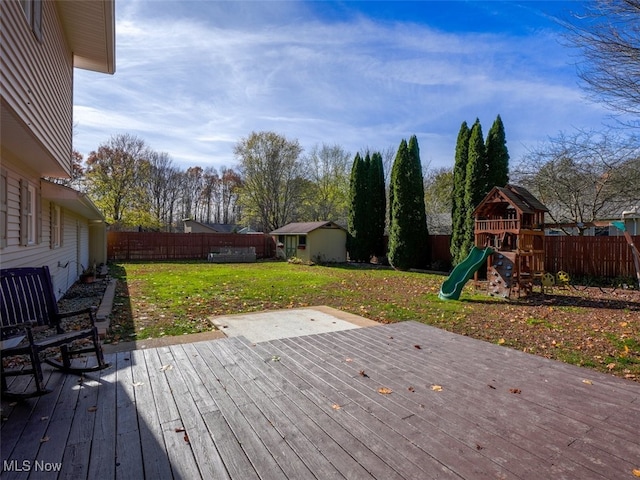 wooden deck with a playground, a storage unit, and a lawn