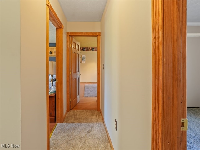 hallway with a textured ceiling and light colored carpet