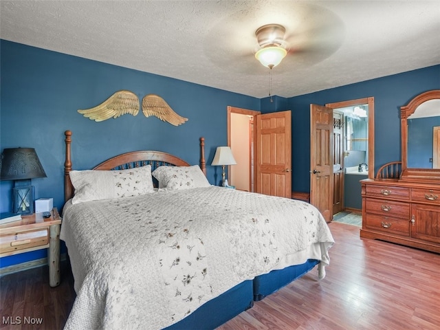 bedroom featuring ceiling fan, ensuite bathroom, wood-type flooring, and a textured ceiling