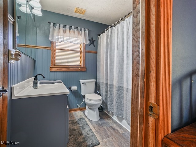 full bathroom featuring shower / bath combination with curtain, a textured ceiling, toilet, vanity, and hardwood / wood-style flooring