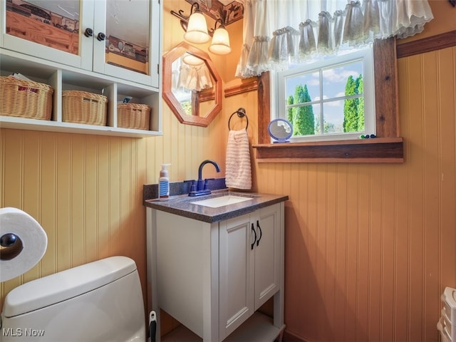 bathroom with wooden walls, vanity, and toilet